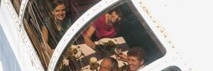 People looking up from dinner thru curved glass on a boat.